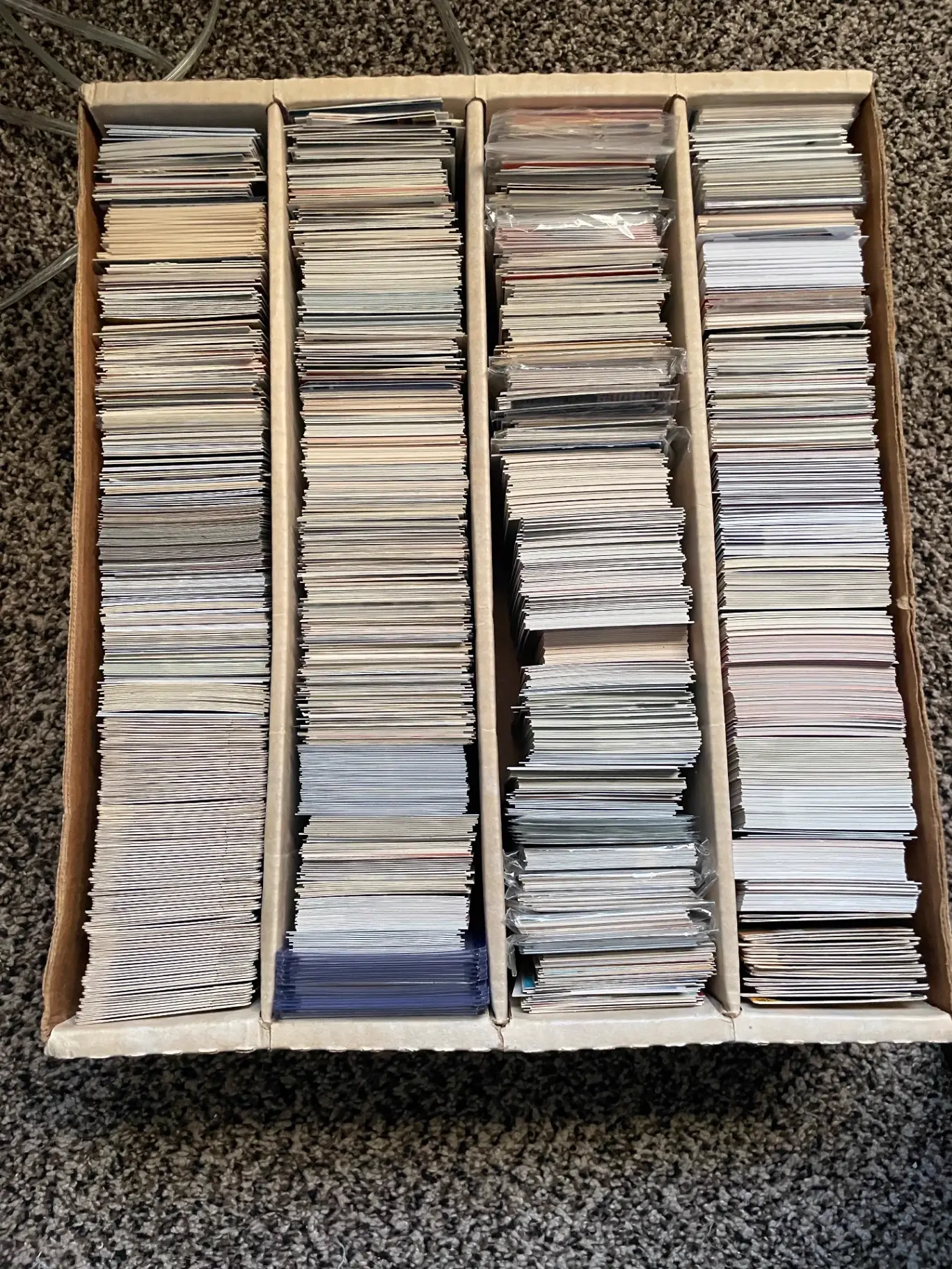 Four-row cardboard box packed with sorted vintage and modern trading cards